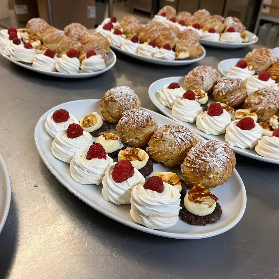 Choux et pavlovas aux framboises dressés sur plats de service