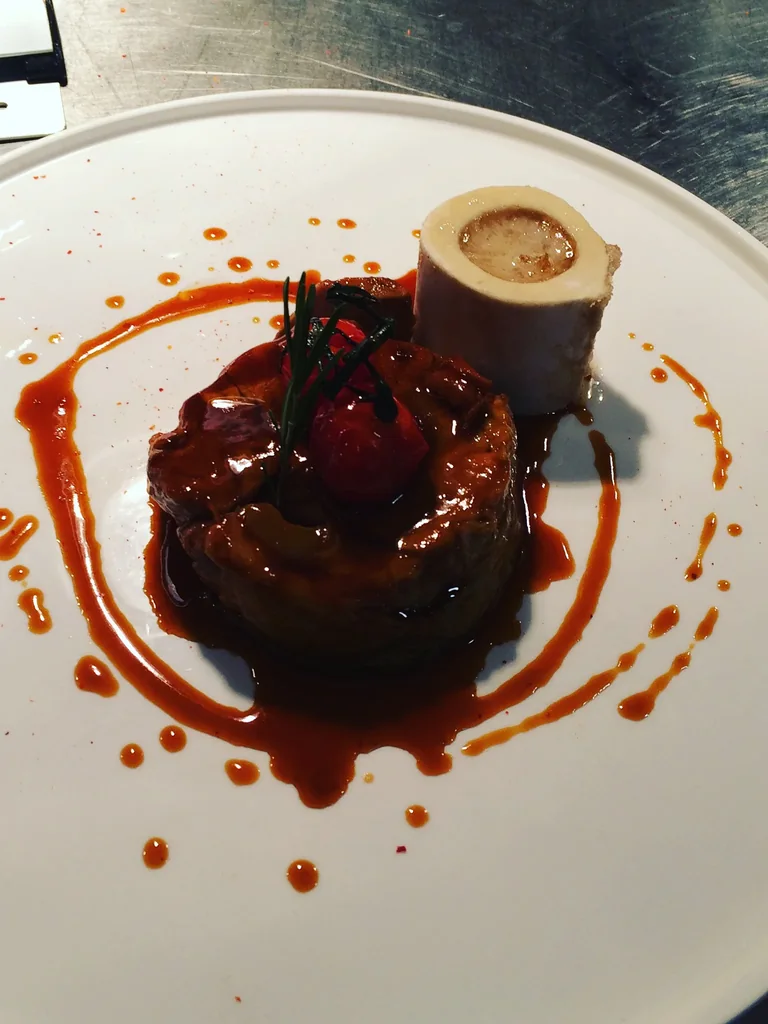 Pièce de viande glacée, sauce réduite et os à moelle