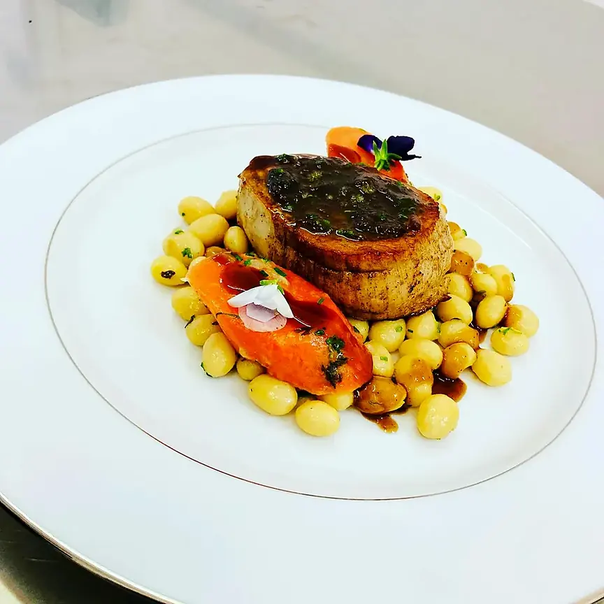Assiette dressée par le chef à domicile : viande, gnocchis et fleurs comestibles