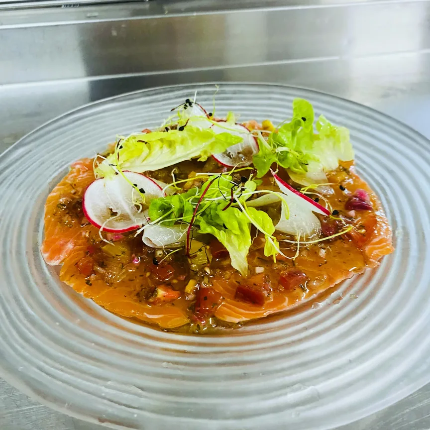 Carpaccio de saumon, radis et jeunes pousses sur assiette en verre